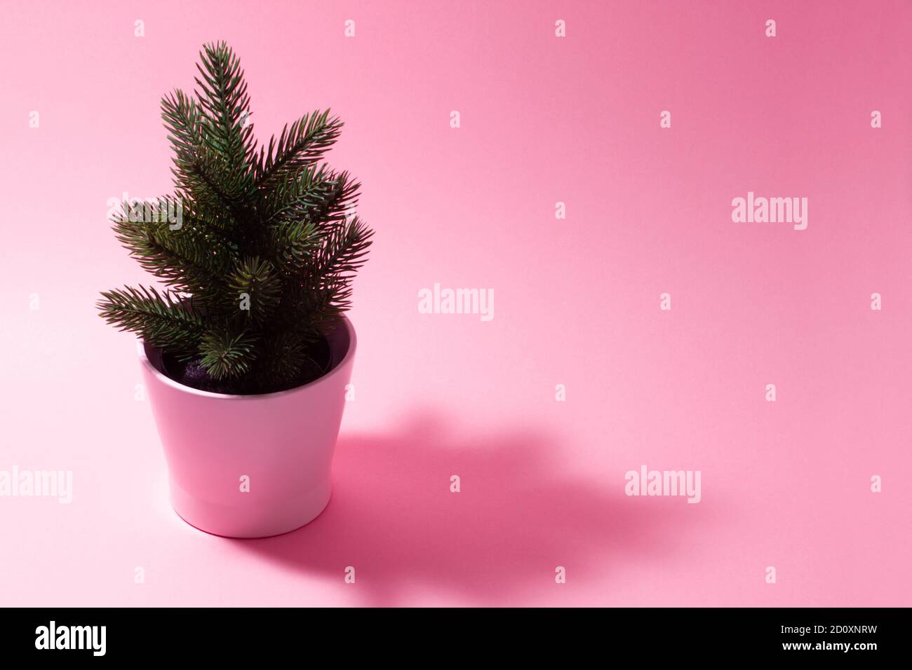 Composition rose pâle sur un nouveau thème de l'année. Un petit sapin de Noël décoratif sur fond rose. Banque D'Images