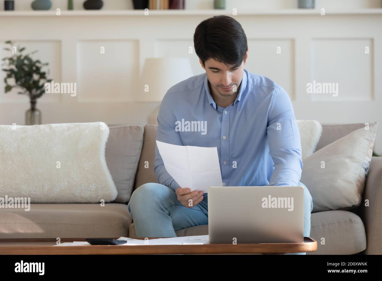 Un homme d'affaires millénaire réfléchi fournit le paiement par Internet en utilisant une application spéciale Banque D'Images