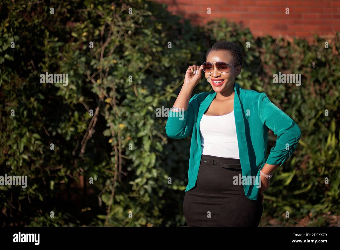 femme noire d'entreprise dans un environnement naturel avec des talons et le soleil lunettes Banque D'Images
