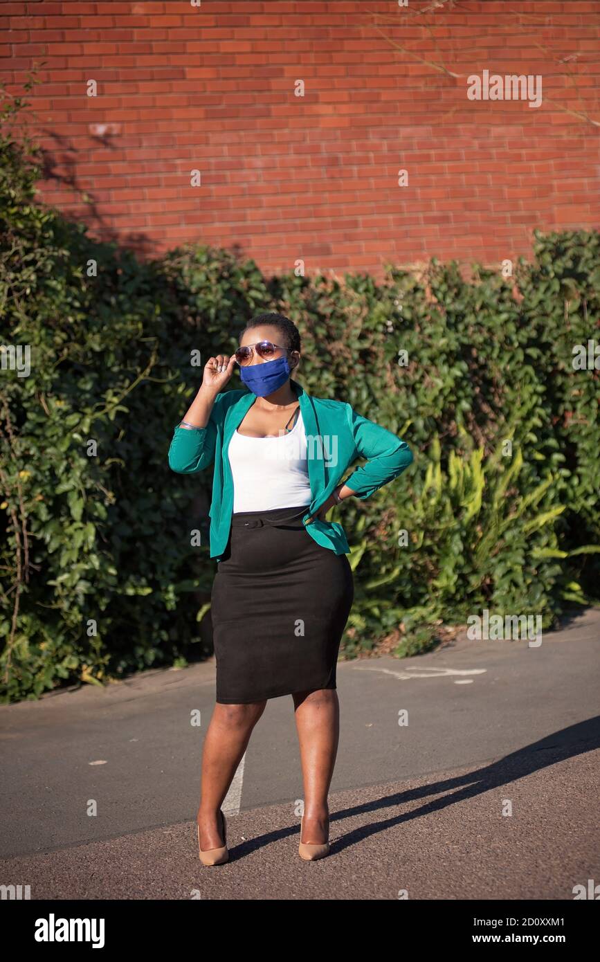 femme noire d'entreprise dans un environnement naturel avec des talons et le soleil lunettes Banque D'Images