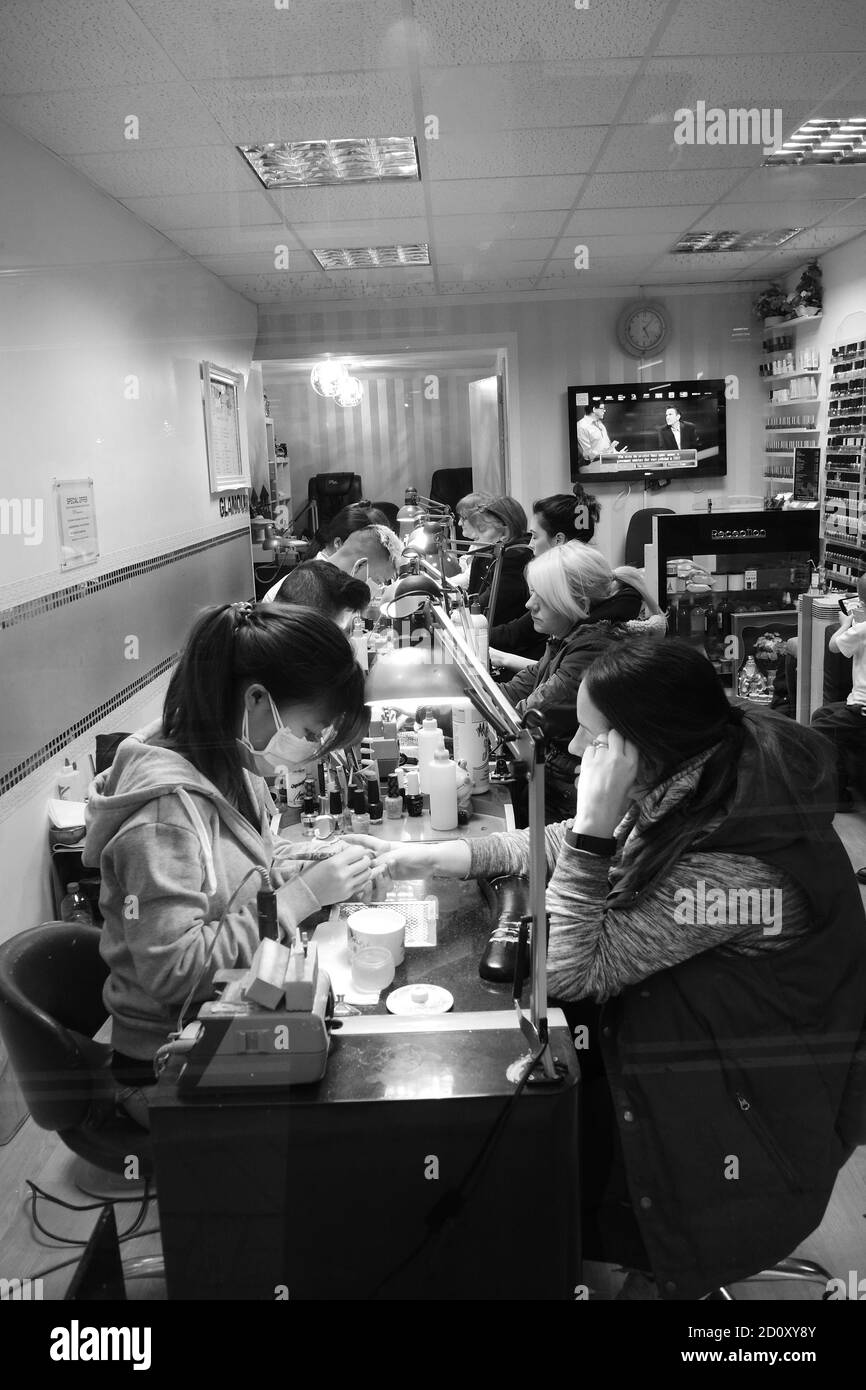 CLIENTS DANS UN MAGASIN DE ONGLES DE DOIGTS DANS LA VILLE DE WORTHING - SUSSEX ANGLETERRE 2016 - PHOTOGRAPHIE NOIR ET BLANC © FREDERIC BEAUMONT Banque D'Images