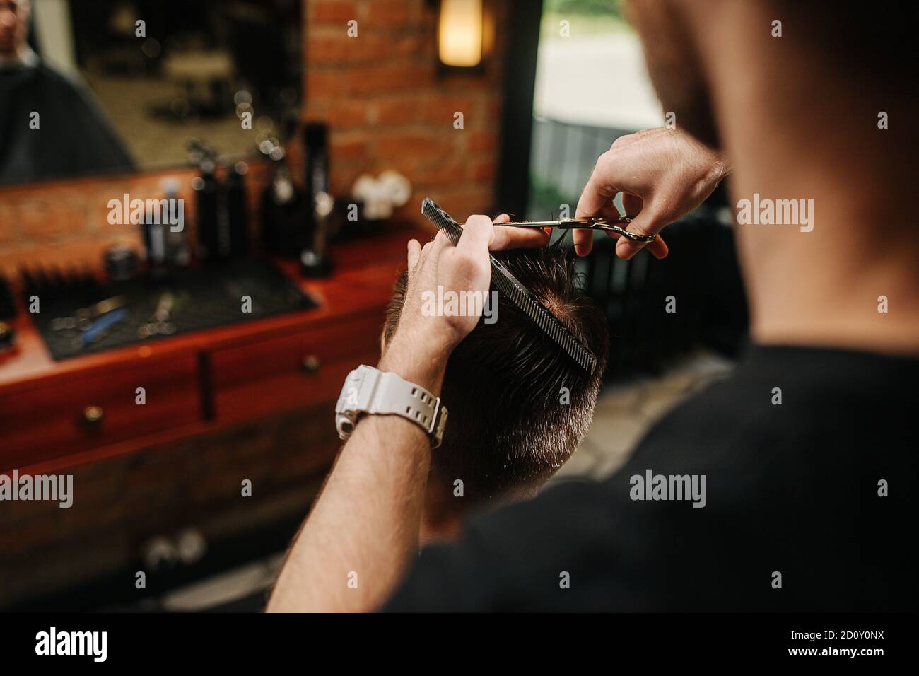 Coiffeur rusé faisant une coupe de cheveux pour un jeune homme dans un salon de coiffure Banque D'Images