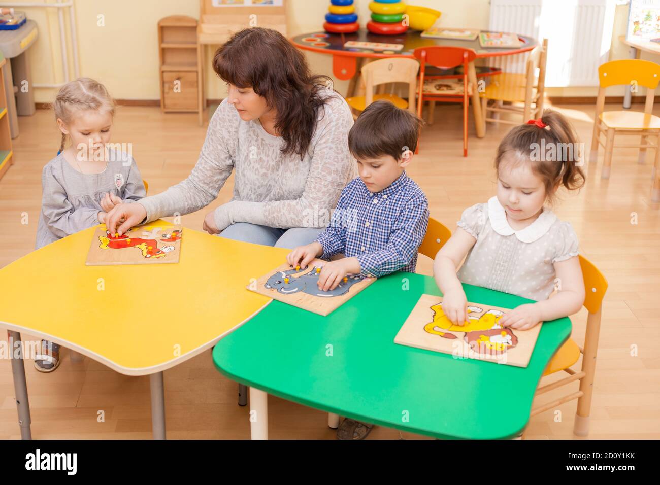 un enseignant de l'école élémentaire recueille un puzzle avec trois élèves Banque D'Images