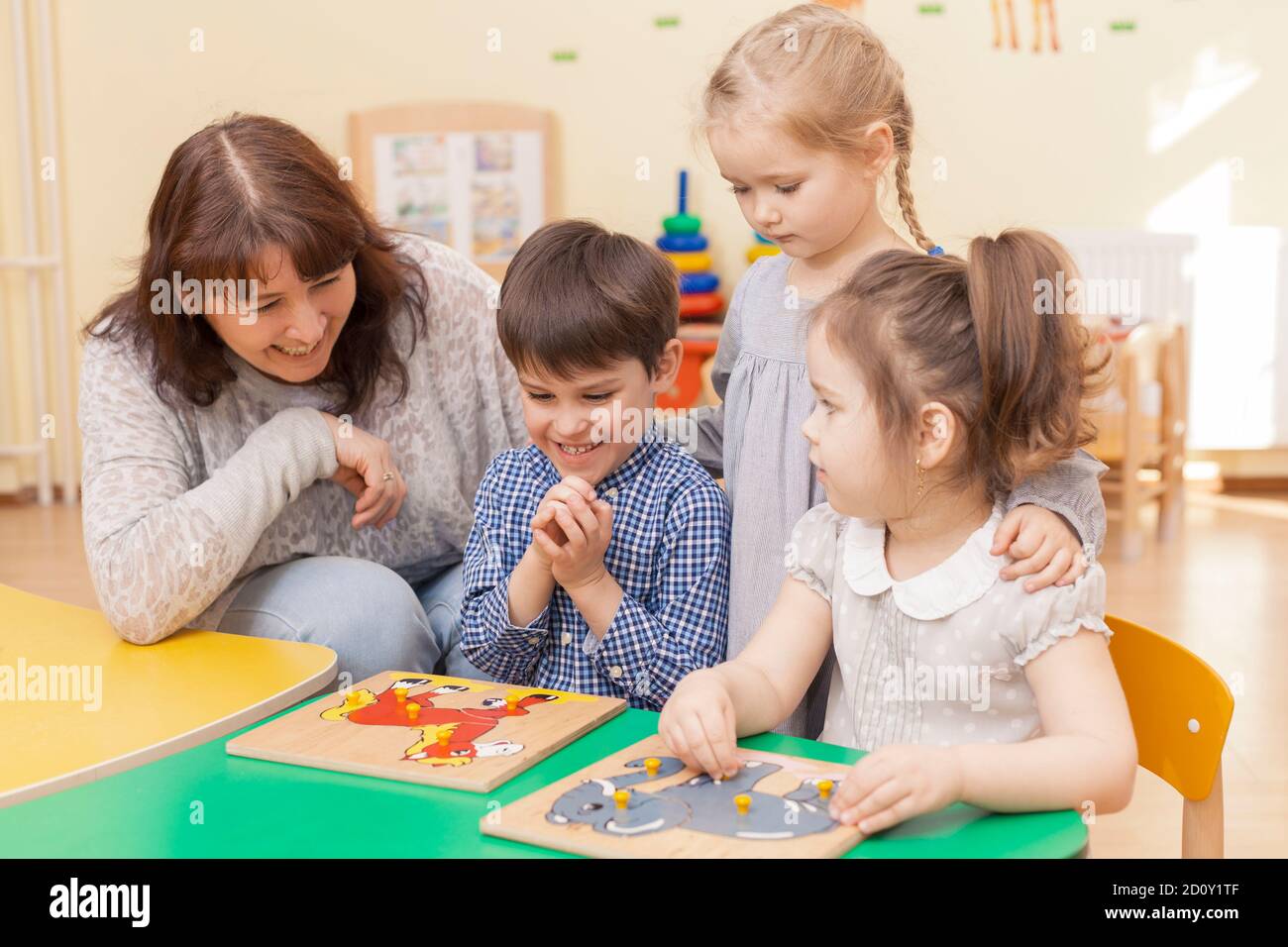 un enseignant de l'école élémentaire recueille un puzzle avec trois élèves Banque D'Images