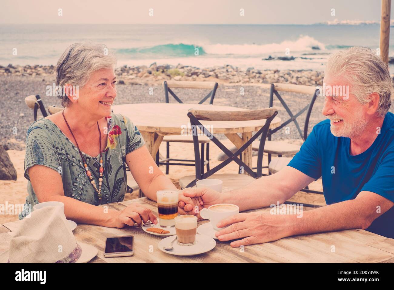 Vieux senior beau couple caucasien appréciez la relation et la vie ensemble boire un café au bar sur la plage - concept de mode de vie à la retraite an Banque D'Images