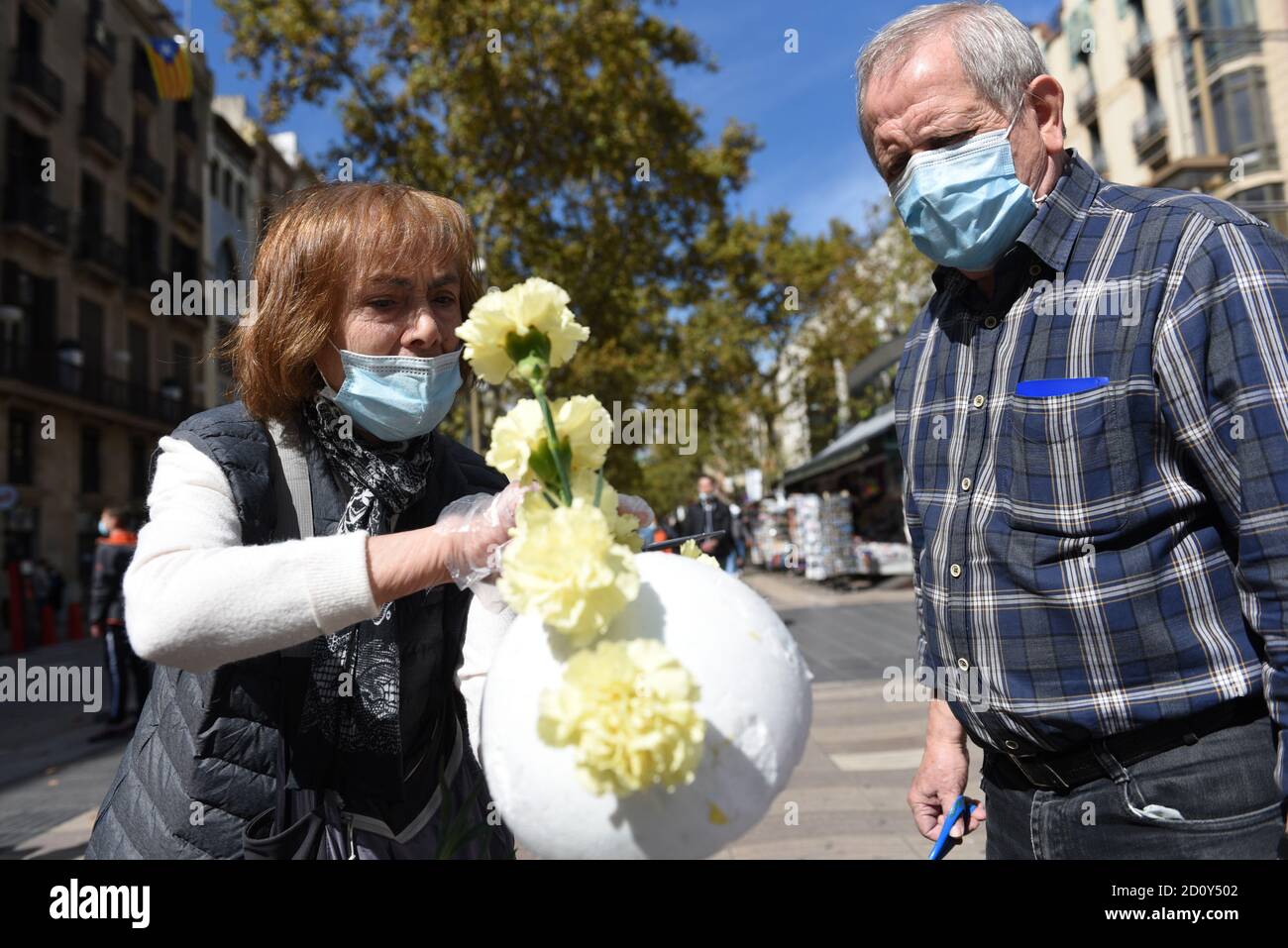 Barcelone, Espagne. 03ème octobre 2020. Une femme portant un masque de visage montre à un homme comment préparer des bouquets de fleurs pendant la célébration du festival de Roser de la Rambla.le festival de Roser a lieu chaque année sans échec depuis 1962. Les voisins de ce quartier dans le centre de Barcelone décorent des rues et des bâtiments avec des fleurs en l'honneur de la Vierge du Rosaire, Saint patron de la célèbre rue la Rambla. Crédit : SOPA Images Limited/Alamy Live News Banque D'Images