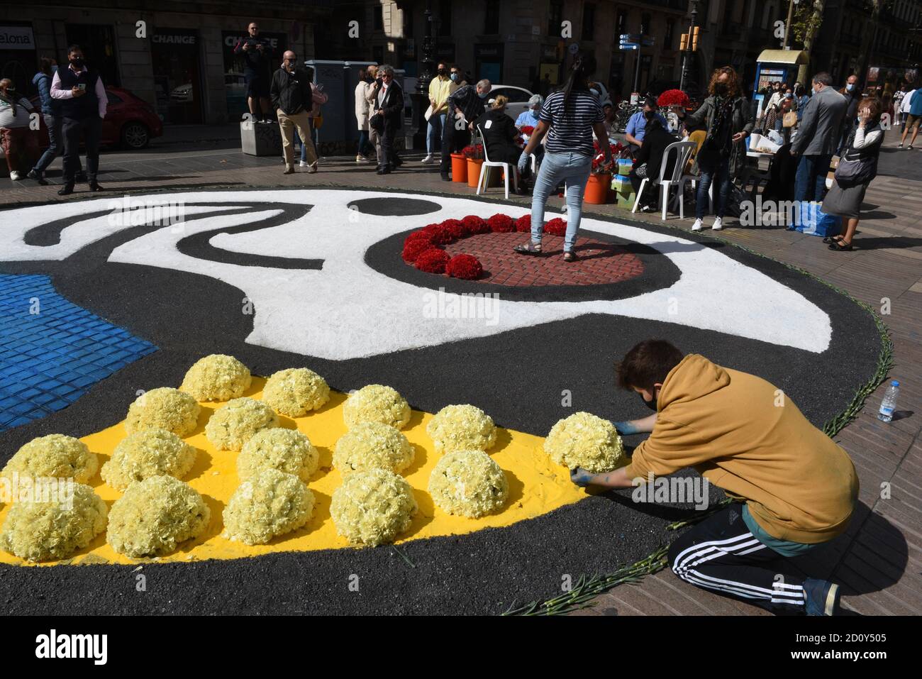 Barcelone, Espagne. 03ème octobre 2020. Une personne portant un masque facemask place des bouquets de fleurs jaunes sur le gorund pendant la célébration du festival Roser de la Rambla.le festival Roser a lieu chaque année sans échec depuis 1962. Les voisins de ce quartier dans le centre de Barcelone décorent des rues et des bâtiments avec des fleurs en l'honneur de la Vierge du Rosaire, Saint patron de la célèbre rue la Rambla. Crédit : SOPA Images Limited/Alamy Live News Banque D'Images