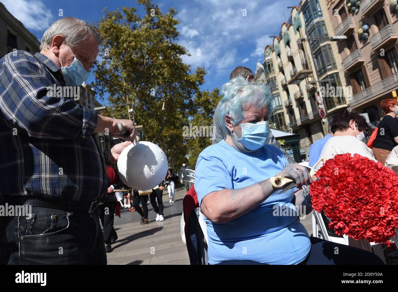 Barcelone, Espagne. 03ème octobre 2020. Un homme portant un masque de visage aide à préparer un bouquet de fleurs pendant la célébration du festival de Roser de la Rambla.le festival de Roser a lieu chaque année sans échec depuis 1962. Les voisins de ce quartier dans le centre de Barcelone décorent des rues et des bâtiments avec des fleurs en l'honneur de la Vierge du Rosaire, Saint patron de la célèbre rue la Rambla. Crédit : SOPA Images Limited/Alamy Live News Banque D'Images