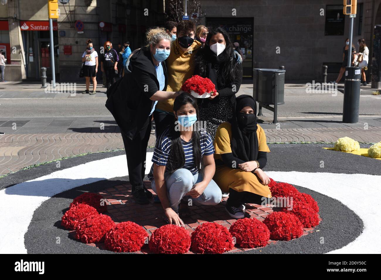 Barcelone, Espagne. 03ème octobre 2020. Les gens portant des masques faciaux posent pour une photo à l'intérieur d'un cercle de bouquets de fleurs pendant la célébration du festival de Roser de la Rambla.le festival de Roser a eu lieu chaque année sans échec depuis 1962. Les voisins de ce quartier dans le centre de Barcelone décorent des rues et des bâtiments avec des fleurs en l'honneur de la Vierge du Rosaire, Saint patron de la célèbre rue la Rambla. Crédit : SOPA Images Limited/Alamy Live News Banque D'Images