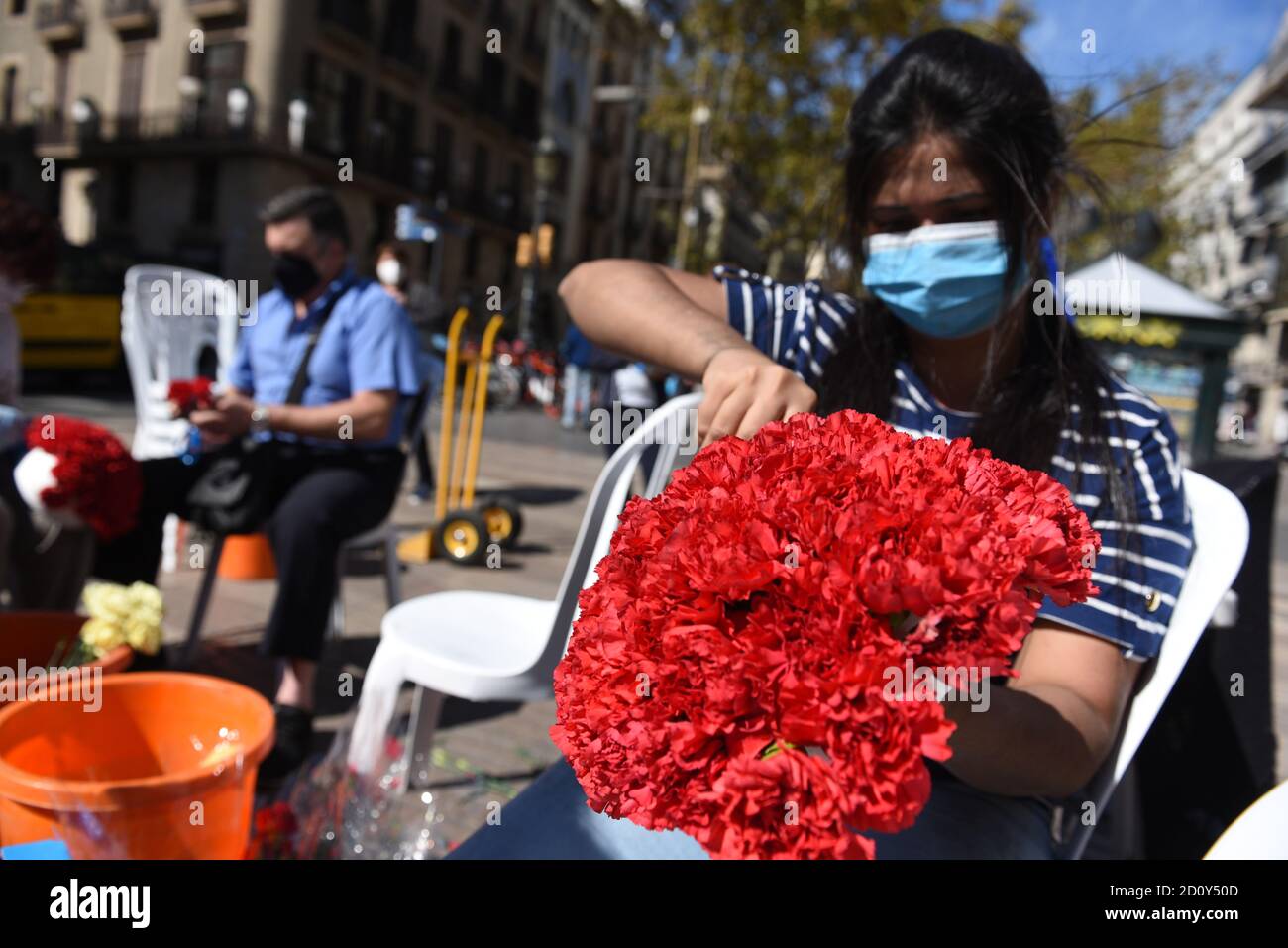 Barcelone, Espagne. 03ème octobre 2020. Une femme portant un masque prépare un bouquet de fleurs lors de la célébration du festival Roser de la Rambla. Le festival Roser a lieu chaque année sans échec depuis 1962. Les voisins de ce quartier dans le centre de Barcelone décorent des rues et des bâtiments avec des fleurs en l'honneur de la Vierge du Rosaire, Saint patron de la célèbre rue la Rambla. Crédit : SOPA Images Limited/Alamy Live News Banque D'Images