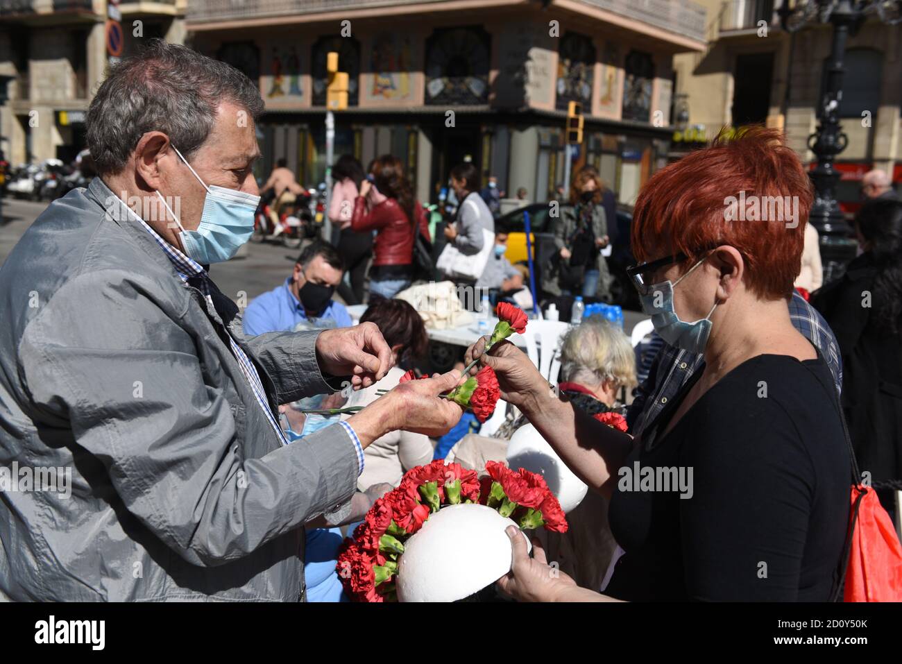 Barcelone, Espagne. 03ème octobre 2020. Les personnes portant des masques faciaux préparent des bouquets de fleurs pendant la célébration du festival de Roser de la Rambla.le festival de Roser a lieu chaque année sans échec depuis 1962. Les voisins de ce quartier dans le centre de Barcelone décorent des rues et des bâtiments avec des fleurs en l'honneur de la Vierge du Rosaire, Saint patron de la célèbre rue la Rambla. Crédit : SOPA Images Limited/Alamy Live News Banque D'Images