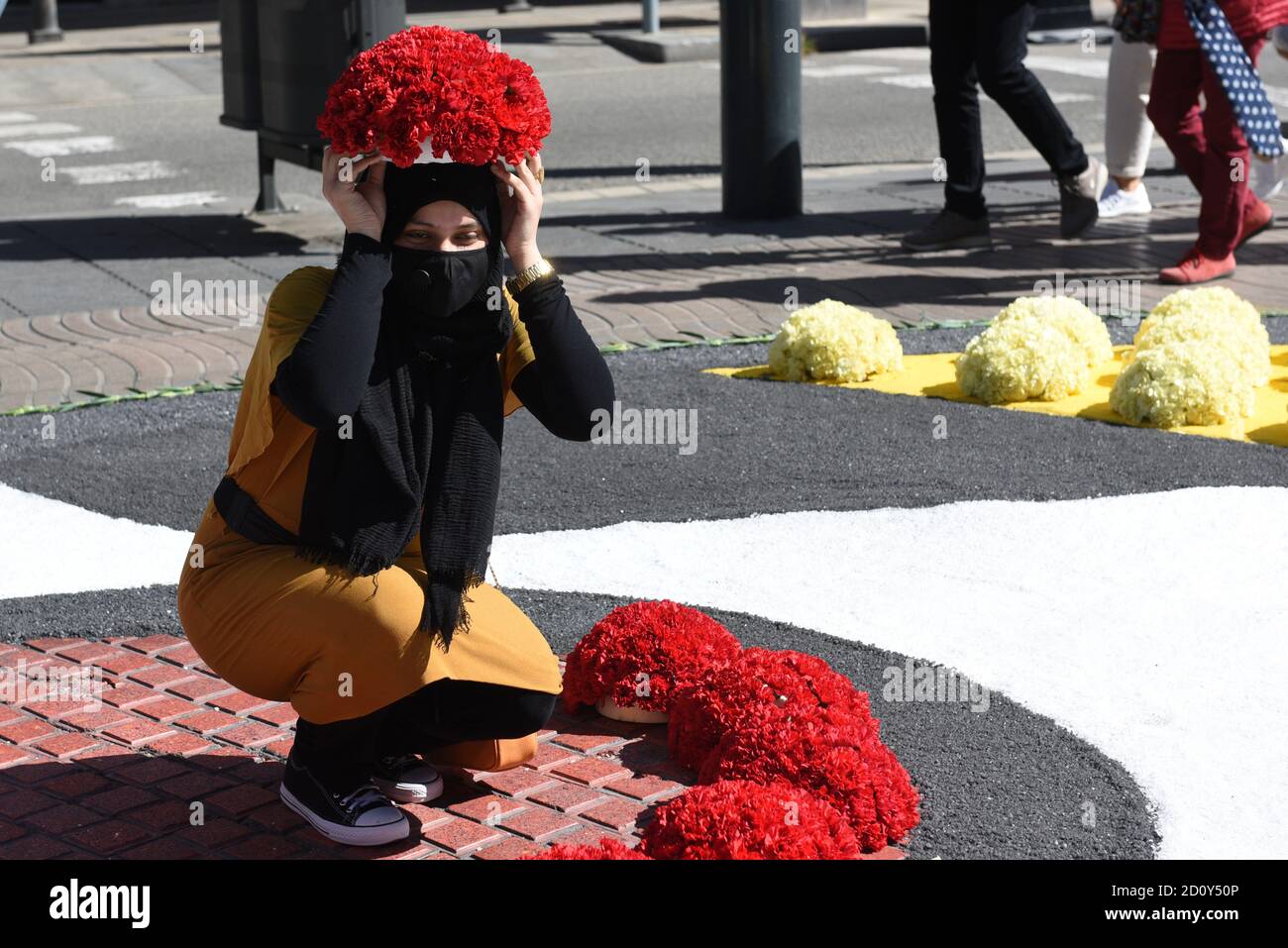 Barcelone, Espagne. 03ème octobre 2020. Une femme portant un masque pose pour une photo avec un bouquet de fleurs sur sa tête pendant la célébration du festival de Roser de la Rambla.le festival de Roser a lieu chaque année sans échec depuis 1962. Les voisins de ce quartier dans le centre de Barcelone décorent des rues et des bâtiments avec des fleurs en l'honneur de la Vierge du Rosaire, Saint patron de la célèbre rue la Rambla. Crédit : SOPA Images Limited/Alamy Live News Banque D'Images