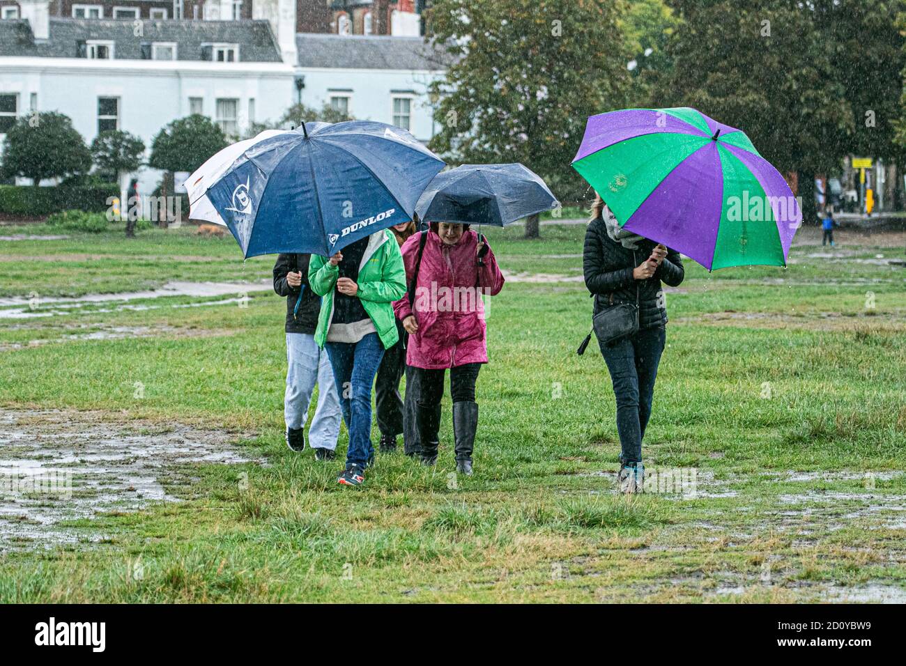 WIMBLEDON LONDRES, ROYAUME-UNI, 4 OCTOBRE 2020. Les gens se réfugient sous des parapluies sur Wimbledon Common dans des conditions humides et venteuses depuis Storm Alex amenant de lourds averses torrentielles et des vents de 70 km/h dans de grandes parties du Royaume-Uni au cours des prochains jours. Credit: amer ghazzal / Alamy Live News Banque D'Images