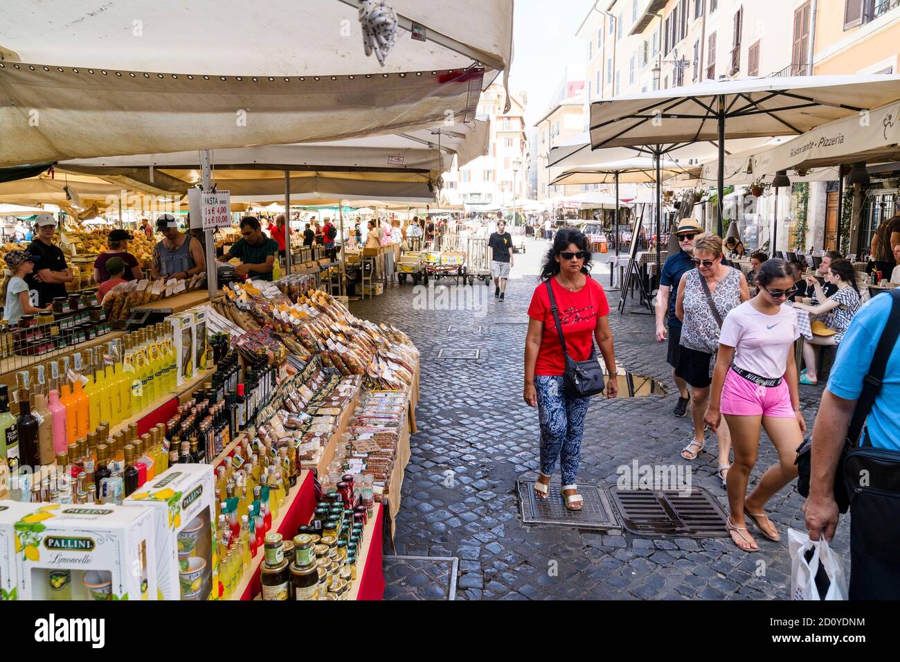 Les gens qui passent devant les étals du marché vendant des huiles en bouteille, des sauces et des paquets d'épices au plus ancien marché de Rome, le Campo dei fiori. Banque D'Images