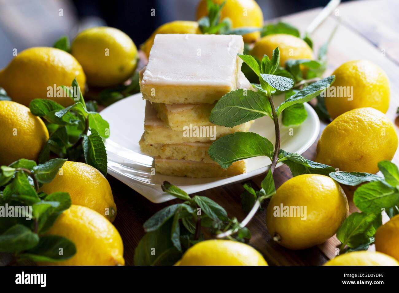 Gâteau authentique, beaucoup de citrons jaunes frais et de menthe. Éclairage d'ambiance matinal, mise au point douce sélective tendance. Préparation à la conception de menus créatifs. Banque D'Images