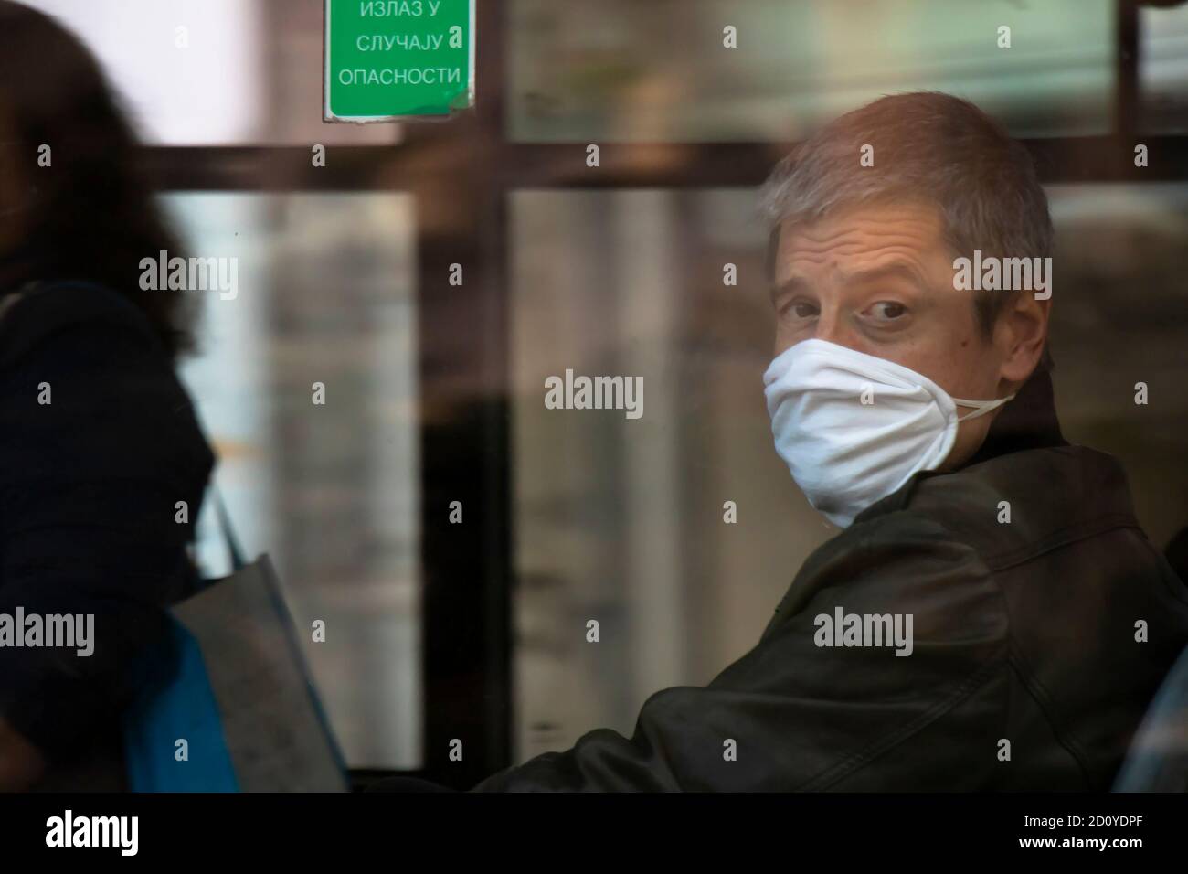 Belgrade, Serbie - 02 octobre 2020 : homme mature portant un masque facial en montant sur un siège de fenêtre dans un bus, à travers la fenêtre Banque D'Images