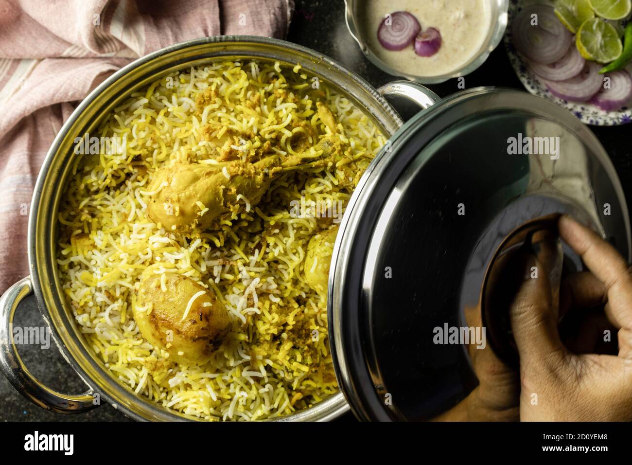 Poulet biryani délicieux et épicé fait maison dans un bol traditionnel avec raita et salade sur fond noir Banque D'Images