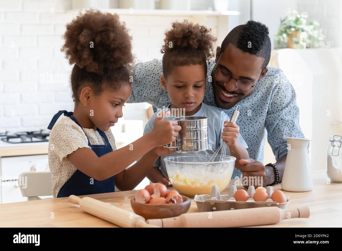 Joyeux afro-américain qui prépare de la pâte avec les enfants. Banque D'Images