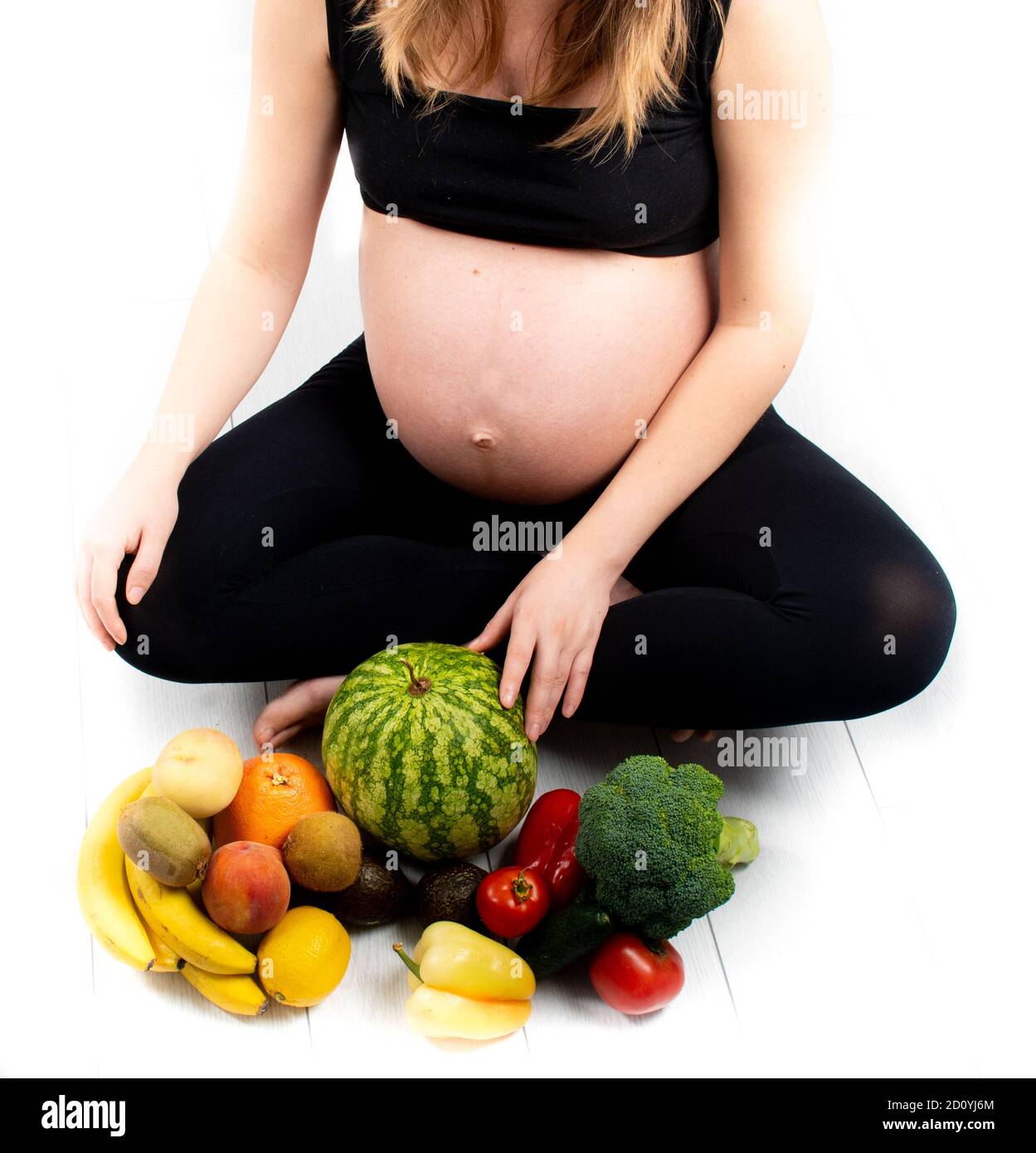 Femme enceinte avec des fruits et des légumes autour d