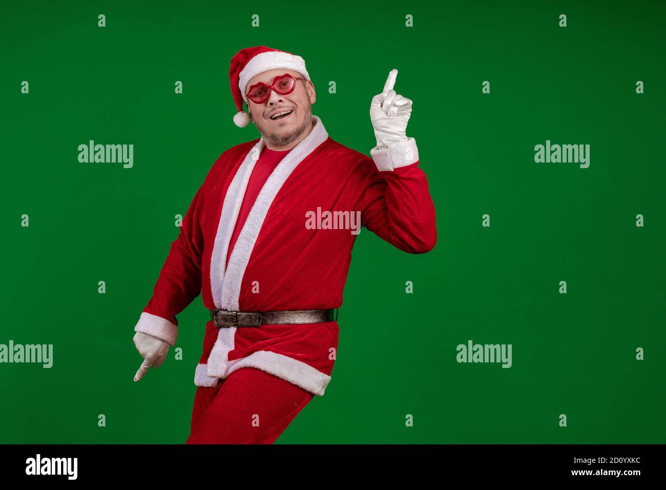 Acteur masculin en costume de Père Noël en rose les lunettes dansant et les  gestes sur un fond rouge foncé Photo Stock - Alamy
