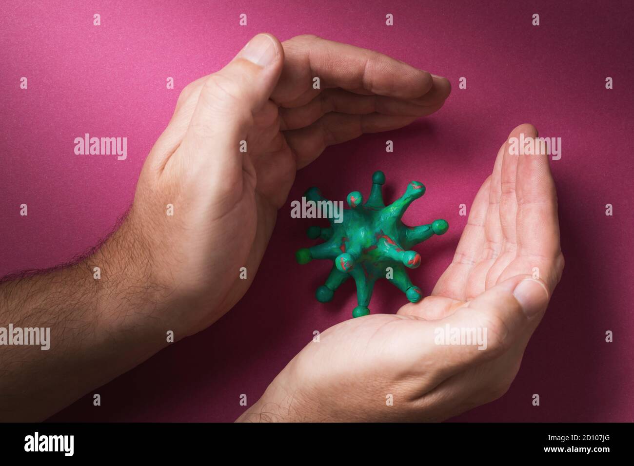 Les mains humaines et le coronavirus jouet. Concept sur le thème de la lutte artificielle contre le virus Banque D'Images