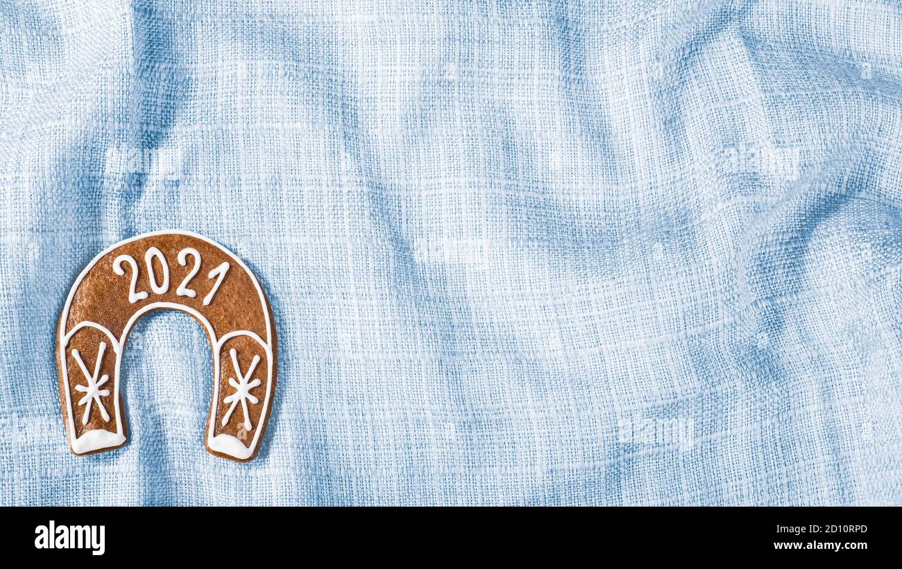 Jeu de fers à cheval pour 2021 Happy Year sur fond textile bleu. Biscuit au pain d'épice au four très orné pour avoir de la chance en forme de chaussure de cheval sur un tissu ondulé. Banque D'Images