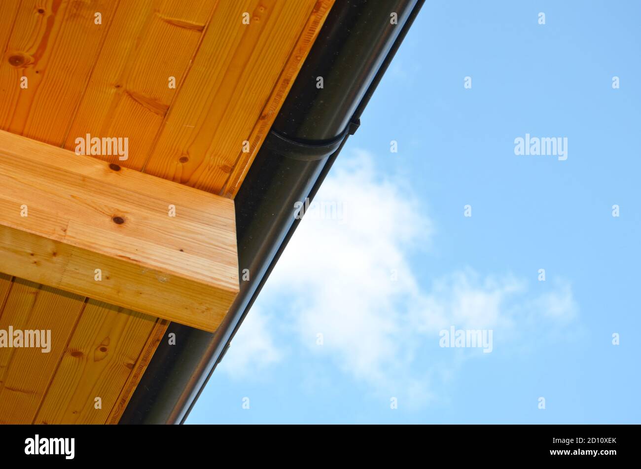 Vue à angle bas d'un toit lambrissé en bois avec drain sur fond bleu ciel. Banque D'Images
