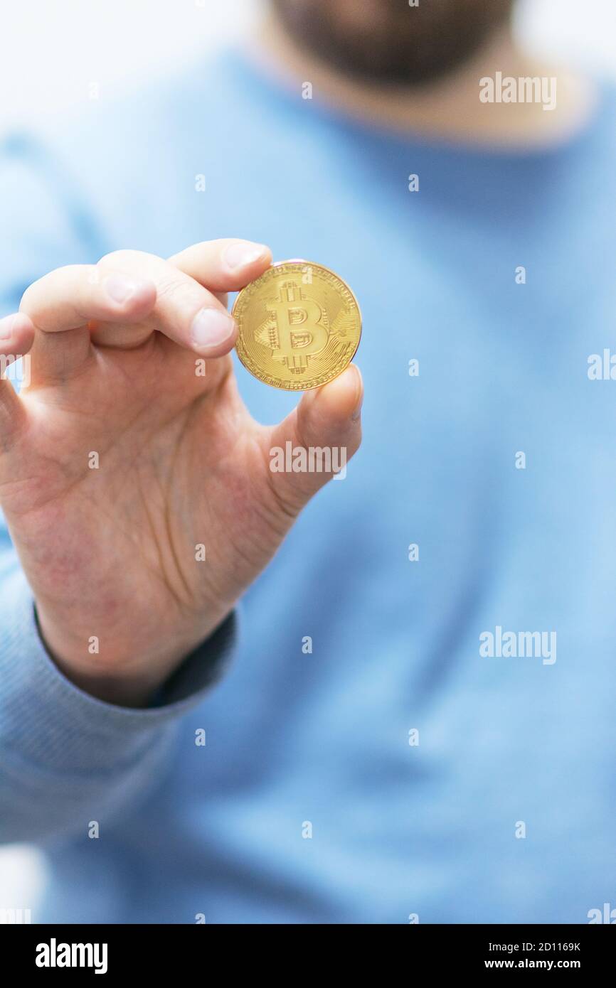 Bitcoin dans les airs. Homme montrant la crypto-monnaie du bitcoin. Concept de crypto-monnaie en métal doré. Banque D'Images