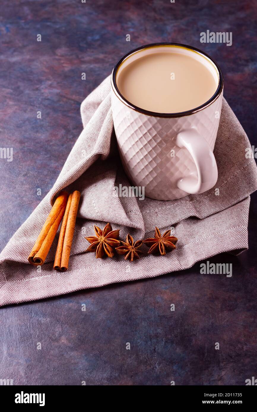 Thé Chai de masala. Boisson traditionnelle indienne - thé masala avec épices sur fond noir. Tasse en céramique d'épices thé sur serviette en lin Banque D'Images