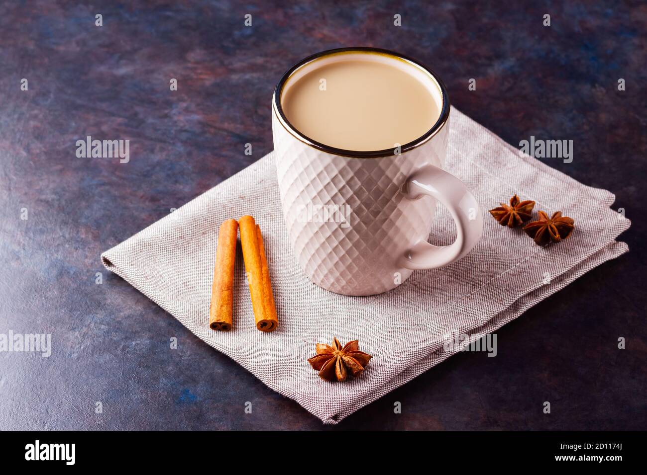 Thé Chai de masala. Boisson traditionnelle indienne - thé masala avec épices sur fond noir. Tasse en céramique d'épices thé sur serviette en lin Banque D'Images