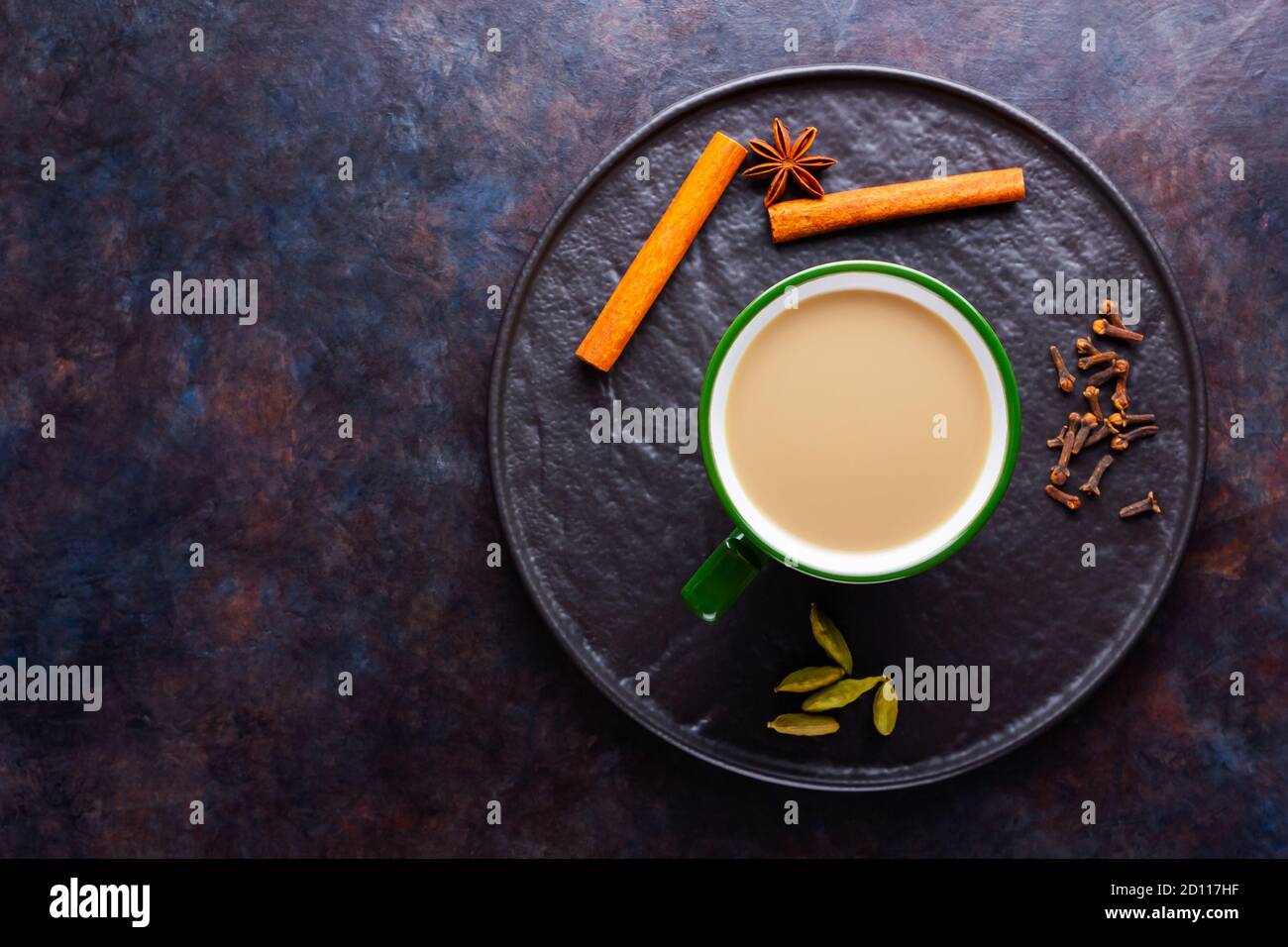 Thé Chai de masala. Boisson traditionnelle indienne - thé masala avec diverses épices sur une assiette noire. Tasse de thé aux épices en céramique sur fond sombre. Minimalis Banque D'Images