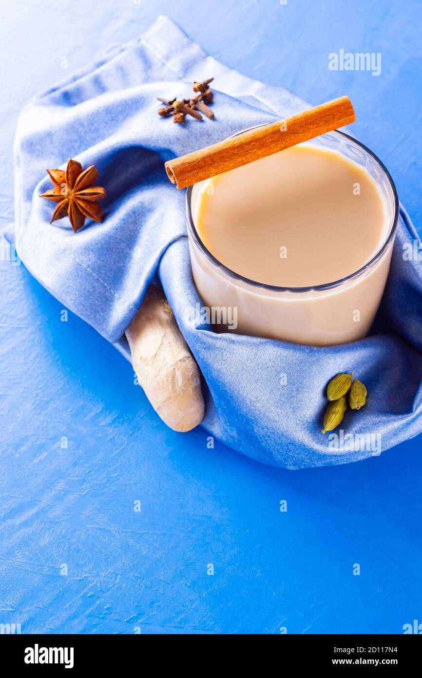 Thé au chaï masala sur une serviette bleue. Boisson traditionnelle indienne - thé masala avec diverses épices. Verre de thé masala sur fond bleu. Copier l'espace Banque D'Images