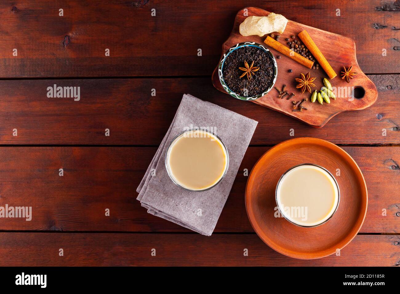 Deux verres de thé masala et divers ingrédients. Thé Chai au masala sur des planches en bois. Thé au lait et épices. Copier l'espace. Vue de dessus Banque D'Images