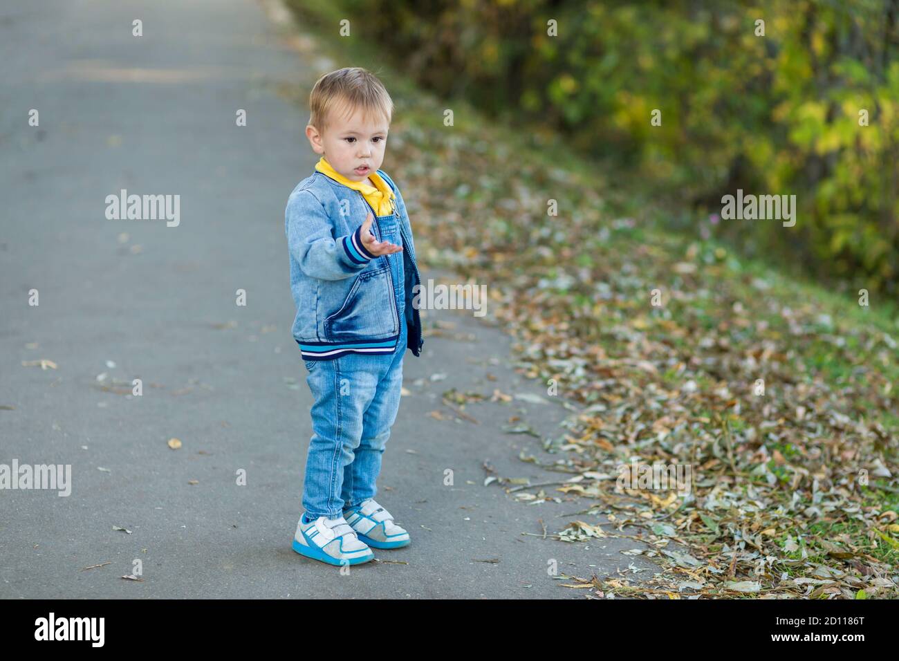 Un petit garçon debout sur le chemin à l'intérieur un parc de la ville Banque D'Images