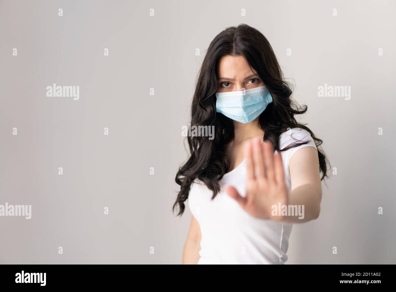 Femme portant un masque pour la protection contre la maladie et montre mains stop geste pour arrêter l'épidémie de virus corona. Un attrait pour rester à la maison. Concept de coronavirus. Banque D'Images