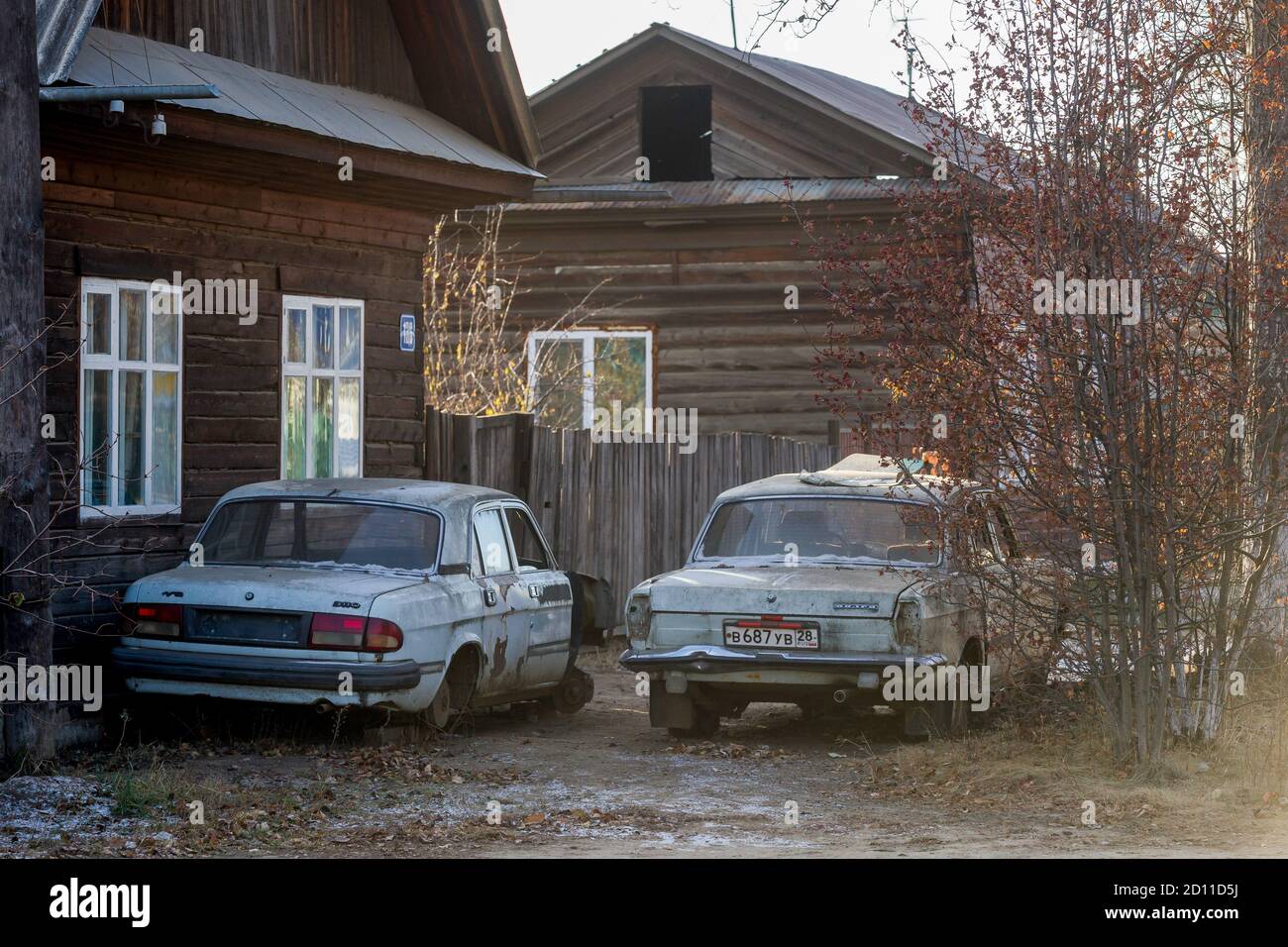 Les voitures de la Volga soviétique se trouvent devant un bois maison de village Banque D'Images