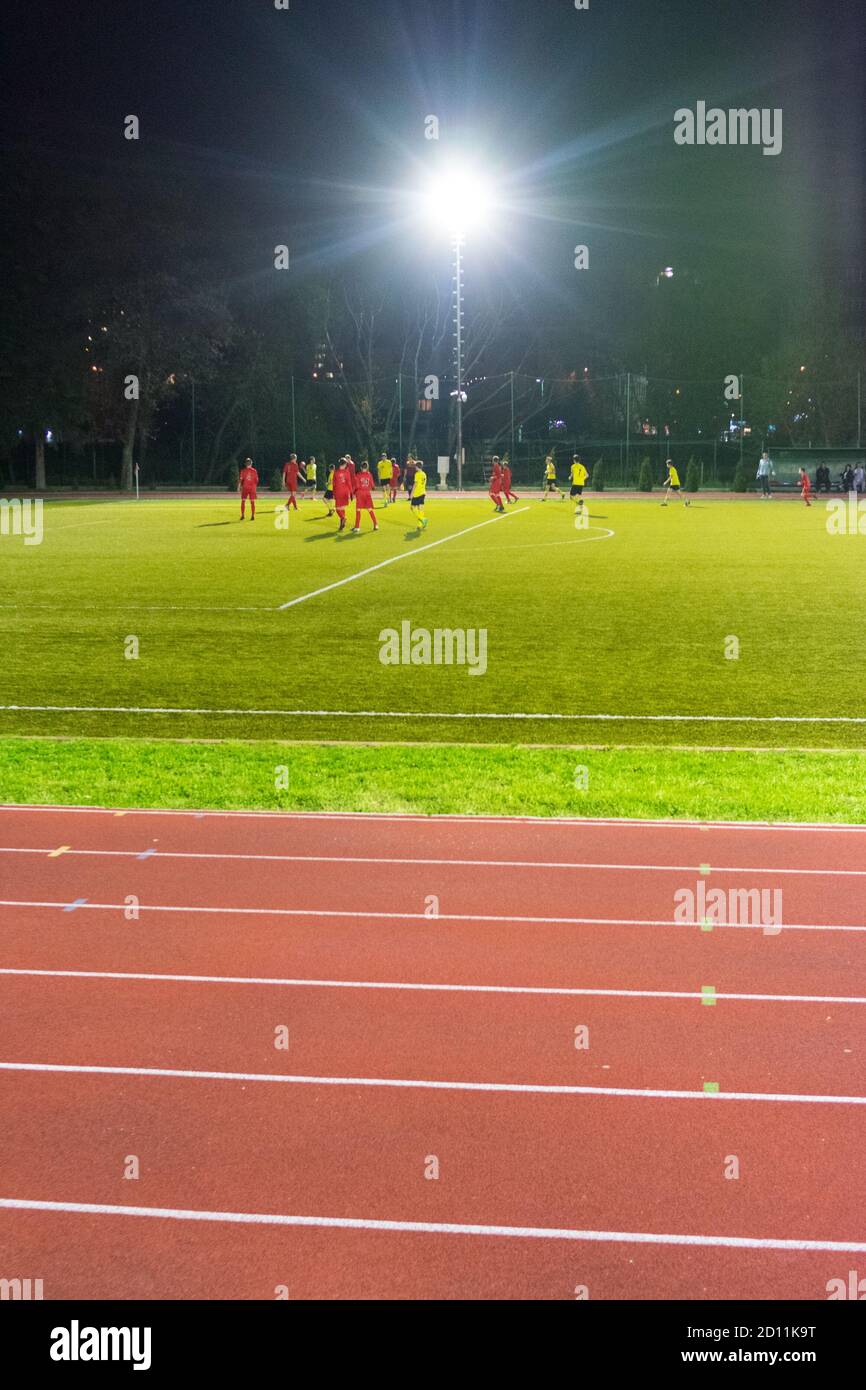 Joueurs jouant un match de football la nuit Banque D'Images