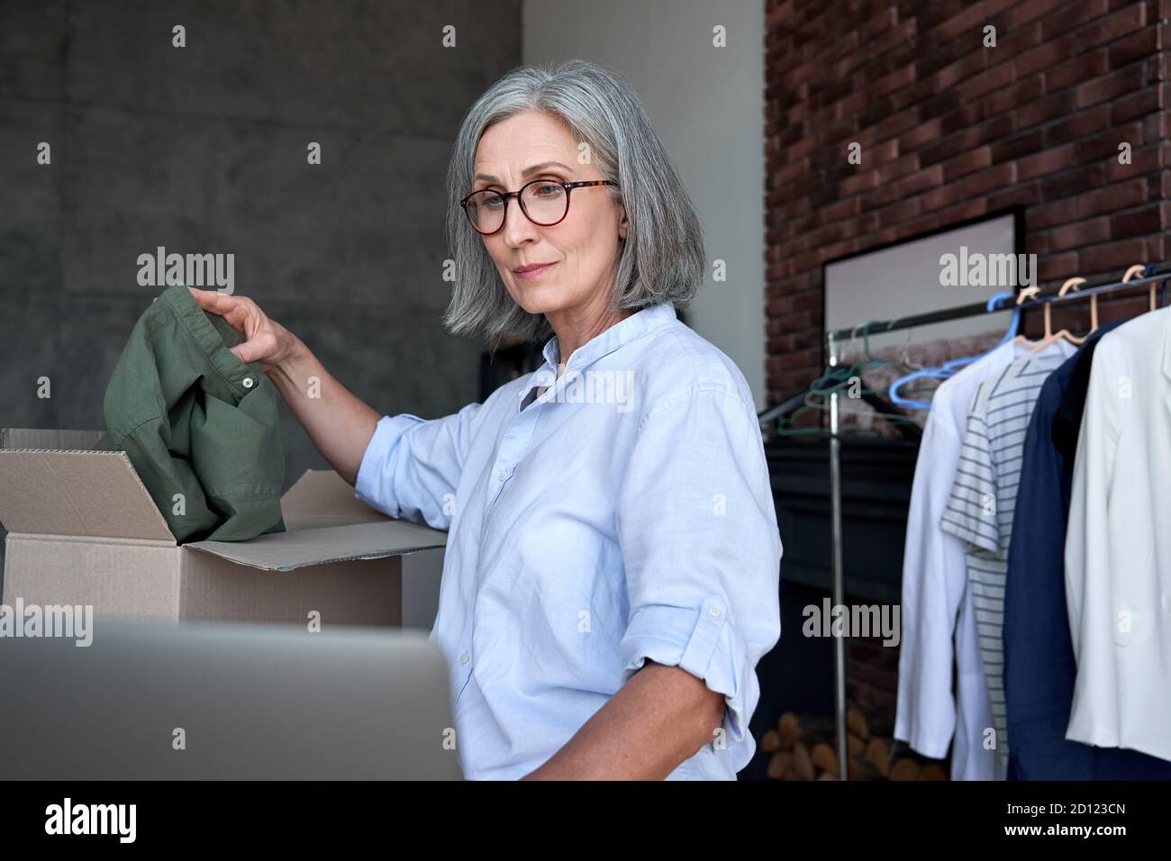 Une femme plus ancienne dropshipping habillement propriétaire d'affaires de paquet de commande dans la boîte d'expédition. Banque D'Images