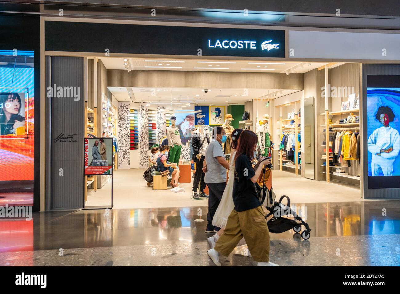 Les piétons marchent devant un magasin Lacoste, détaillant français de mode et de vêtements de sport. Banque D'Images