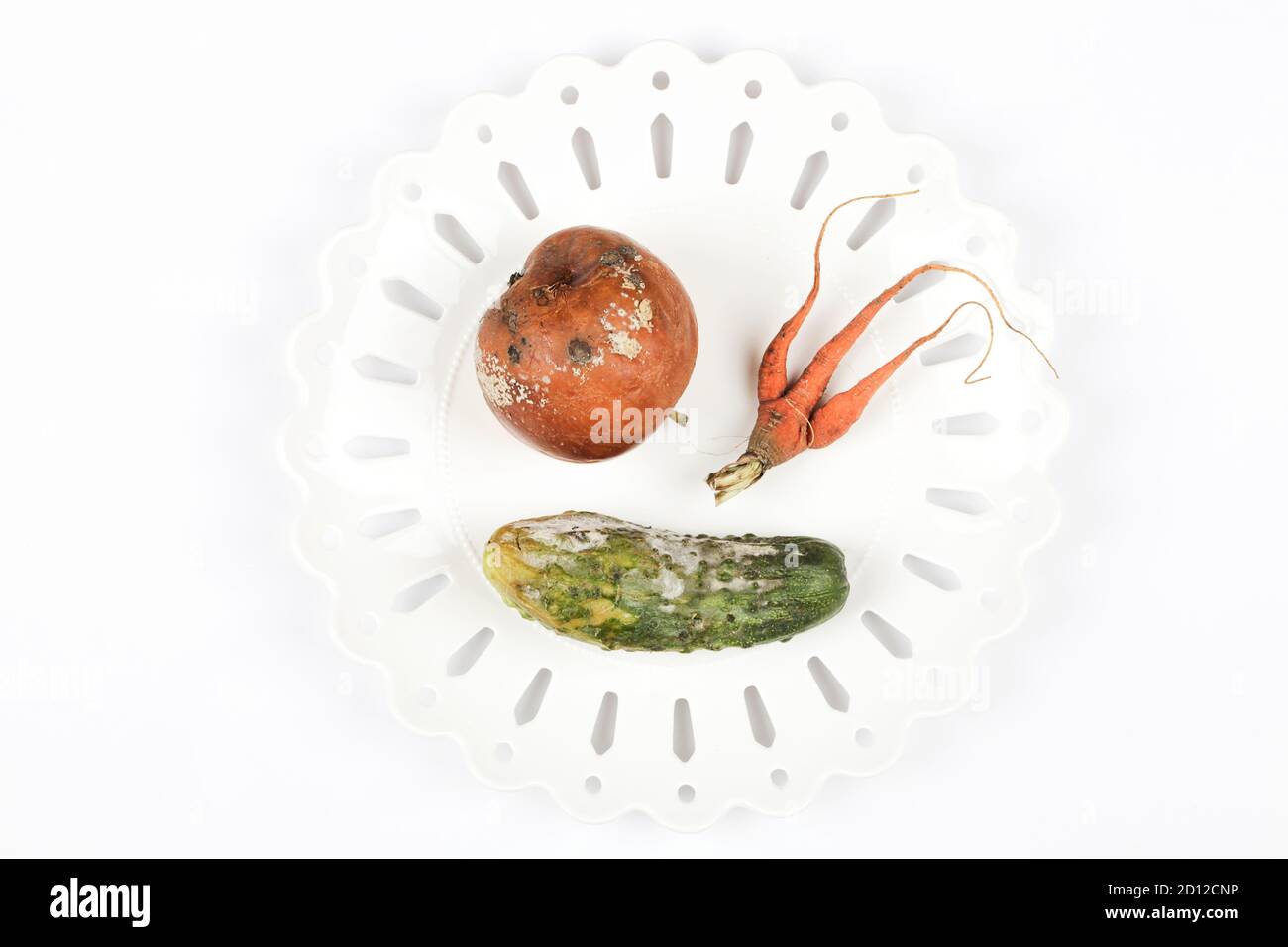 pomme pourrie, concombre, carotte sur plaque sur fond blanc. problème de faim dans le monde. concept de surconsommation. vue du dessus copie espace bannière Banque D'Images