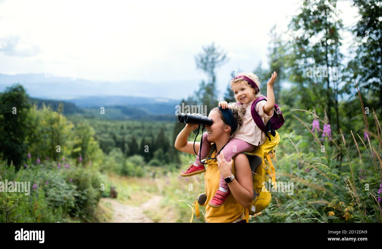 Mère avec petite fille de randonnée à l'extérieur en été nature, en utilisant des jumelles. Banque D'Images