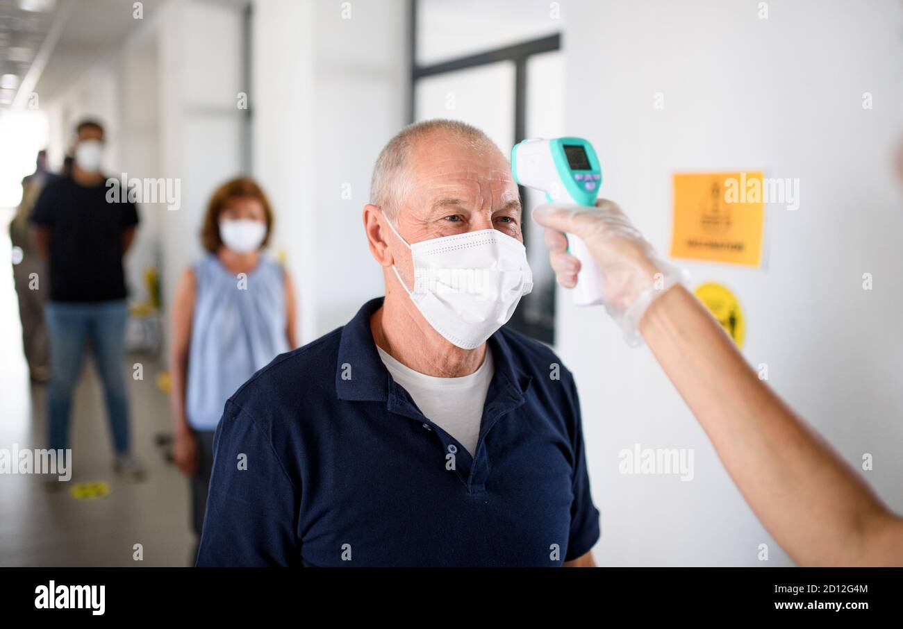 Mesure de la température de l'homme âgé, du coronavirus, du covid-19 et du concept de vaccination. Banque D'Images