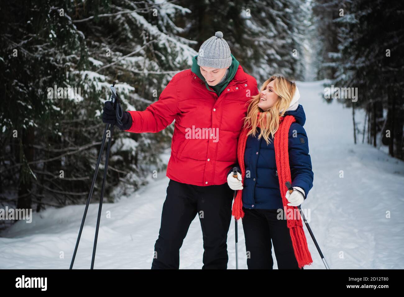 Un couple marié s'apprécie l'un l'autre, l'odeur, le silence et l'unité lors d'une matinée hivernale glaciale à skis dans une forêt d'épicéa. Banque D'Images