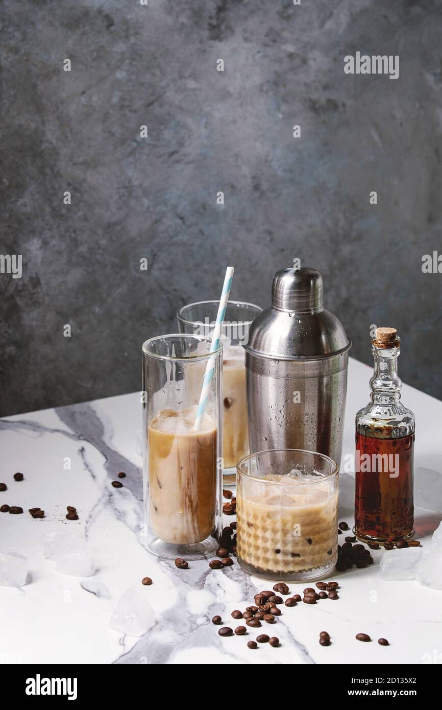 Cocktail café glacé frappe) avec des cubes de glace et de la crème dans des  verres avec silver shaker, bouteille de rhum, les grains de café autour de  marbre blanc sur ta