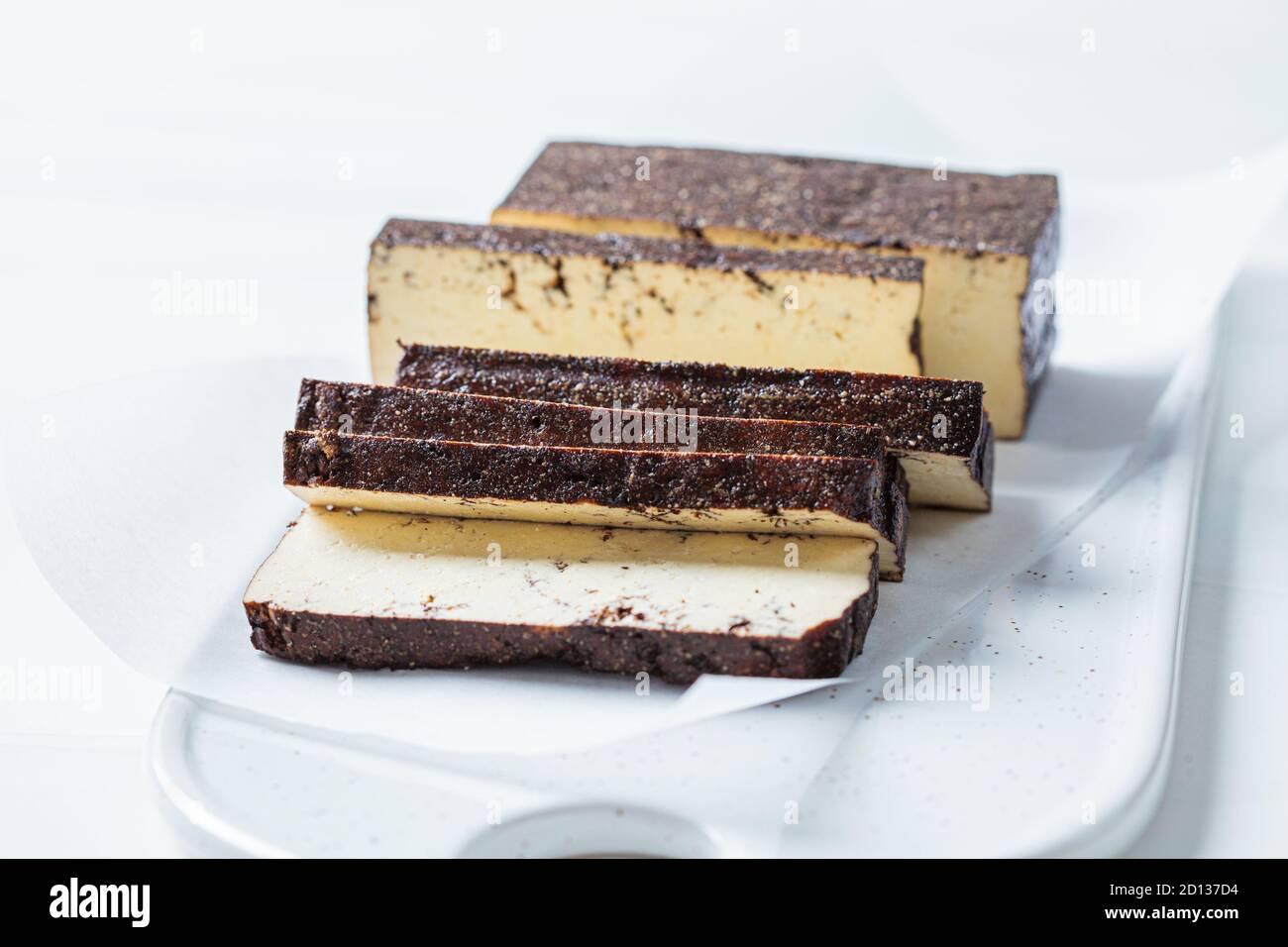 Tranché de tofu fumé sur un tableau blanc, fond blanc. Concept alimentaire végétalien. Banque D'Images