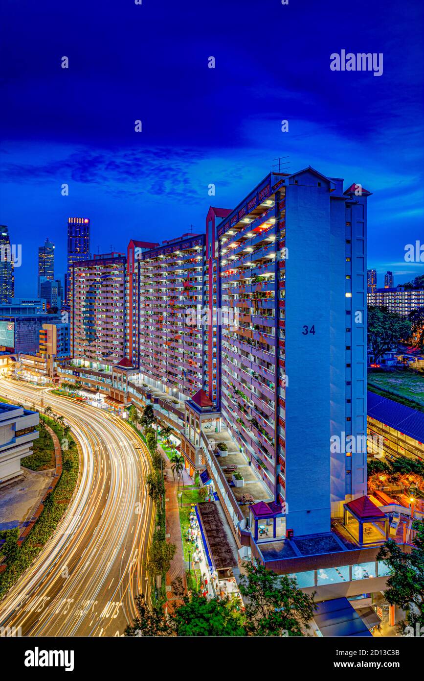 Longue exposition de voitures des sentiers lumineux dans la ville de Singapour contre architecture résidentielle et emblématique, urbaine et patrimoniale Banque D'Images