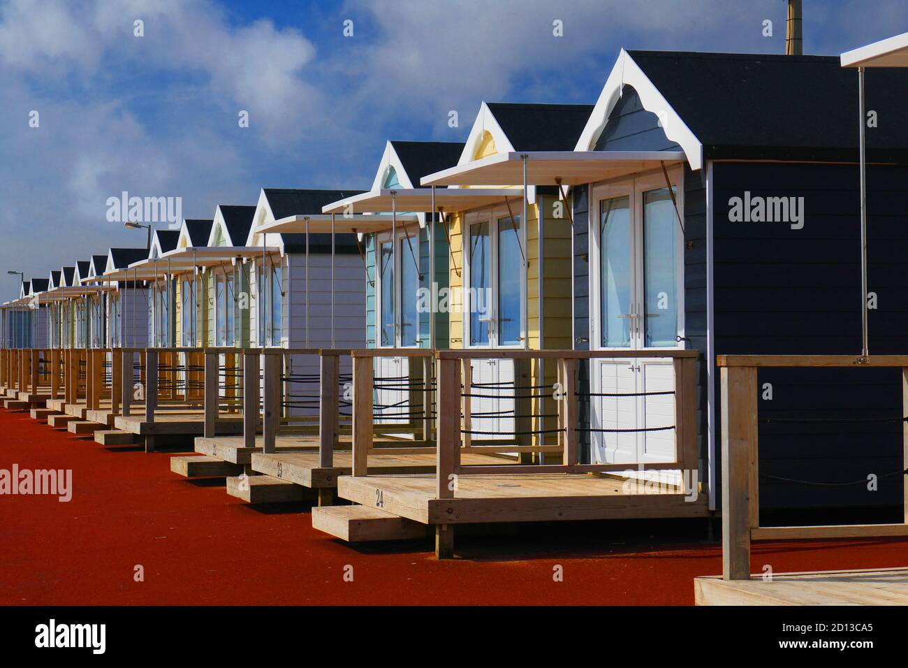 Chalets de plage anglais colorés en bord de mer. Traditionnel typique. Ciel bleu et nuages Banque D'Images