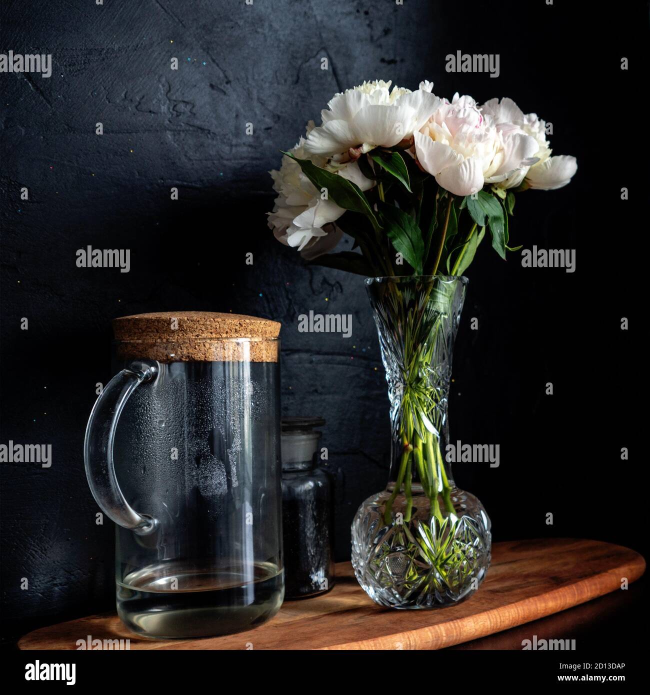 Des pivoines blanches magnifiques et luxuriantes dans un vase sur fond noir, bouquet à la maison. Banque D'Images