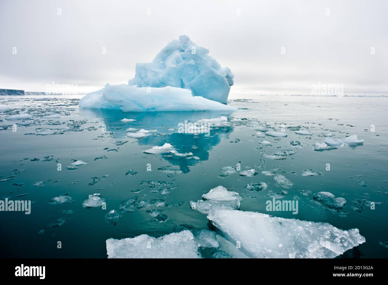 Une vue large à angle bas des glaciers de mer en fonte Dans les eaux fixes de l'Arctique du Nord avec iceberg et glacial paroi en arrière-plan Banque D'Images