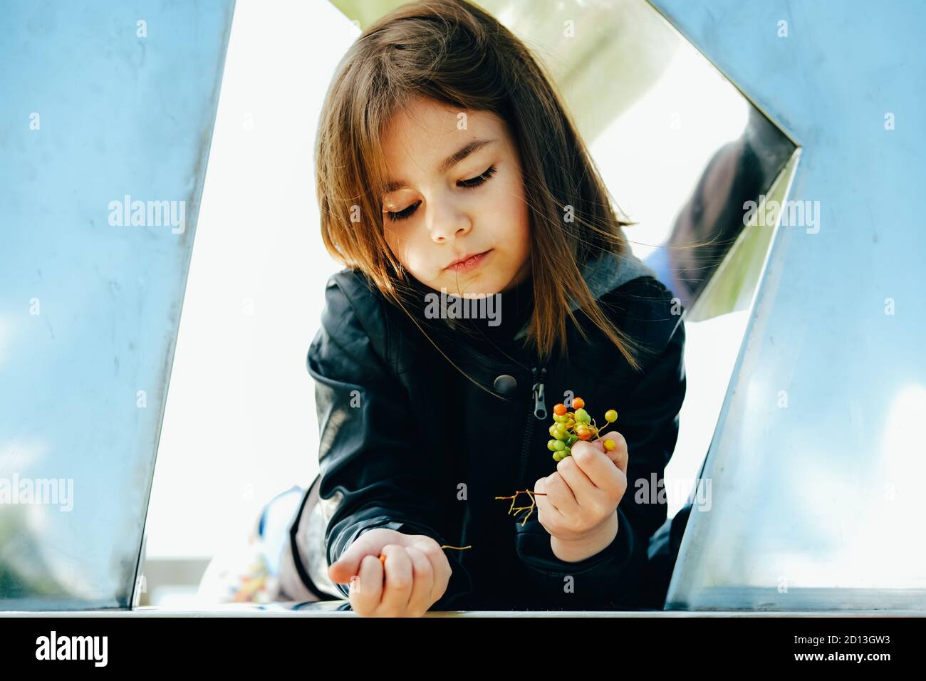 Petite fille dans un élégant ensemble noir d'automne dans un cadre urbain à la recherche du ciel. Banque D'Images